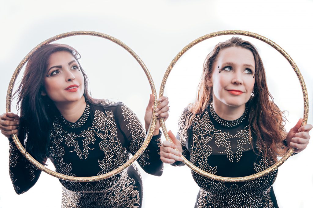 hoop dancers with black costumes and gold hoops