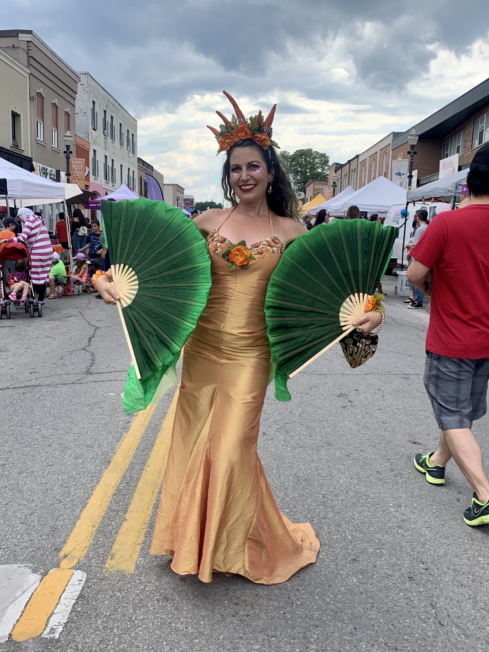 carrot queen at a fair with orange dress and green silk fans