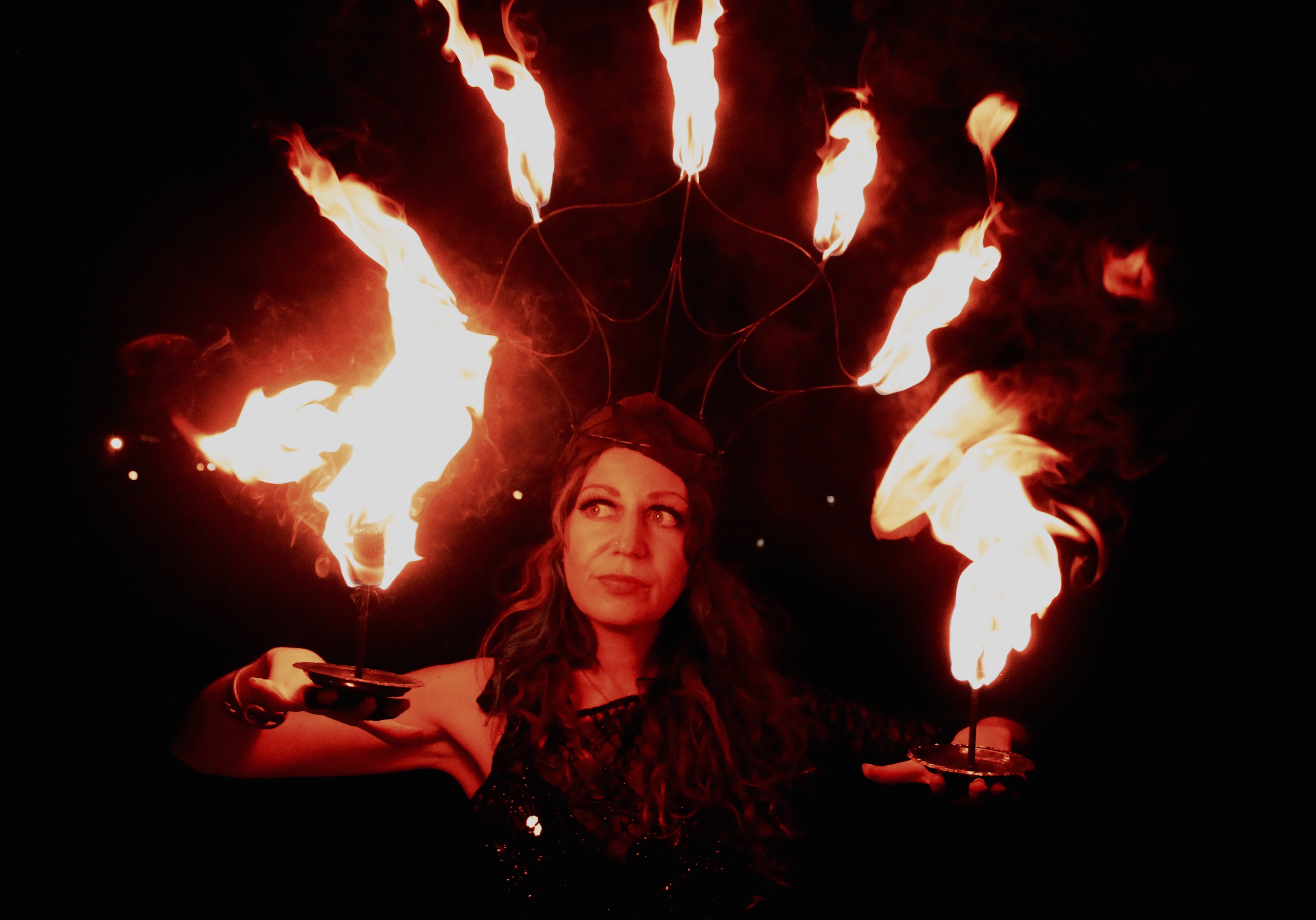 fire headress and fire palm torches on a dancer with eyes looking up