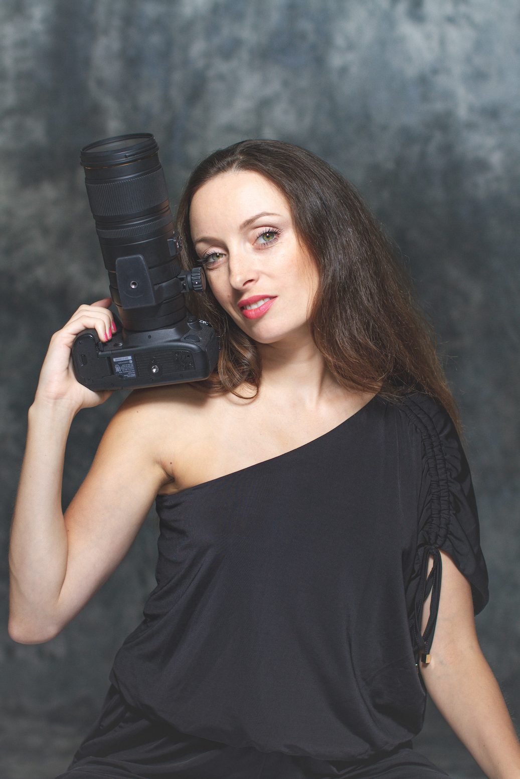 Alissa Baltazar poses with a black camera wearing a black shirt